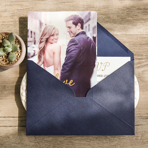 Invitación de boda con foto sobre azul y detalles en dorado.